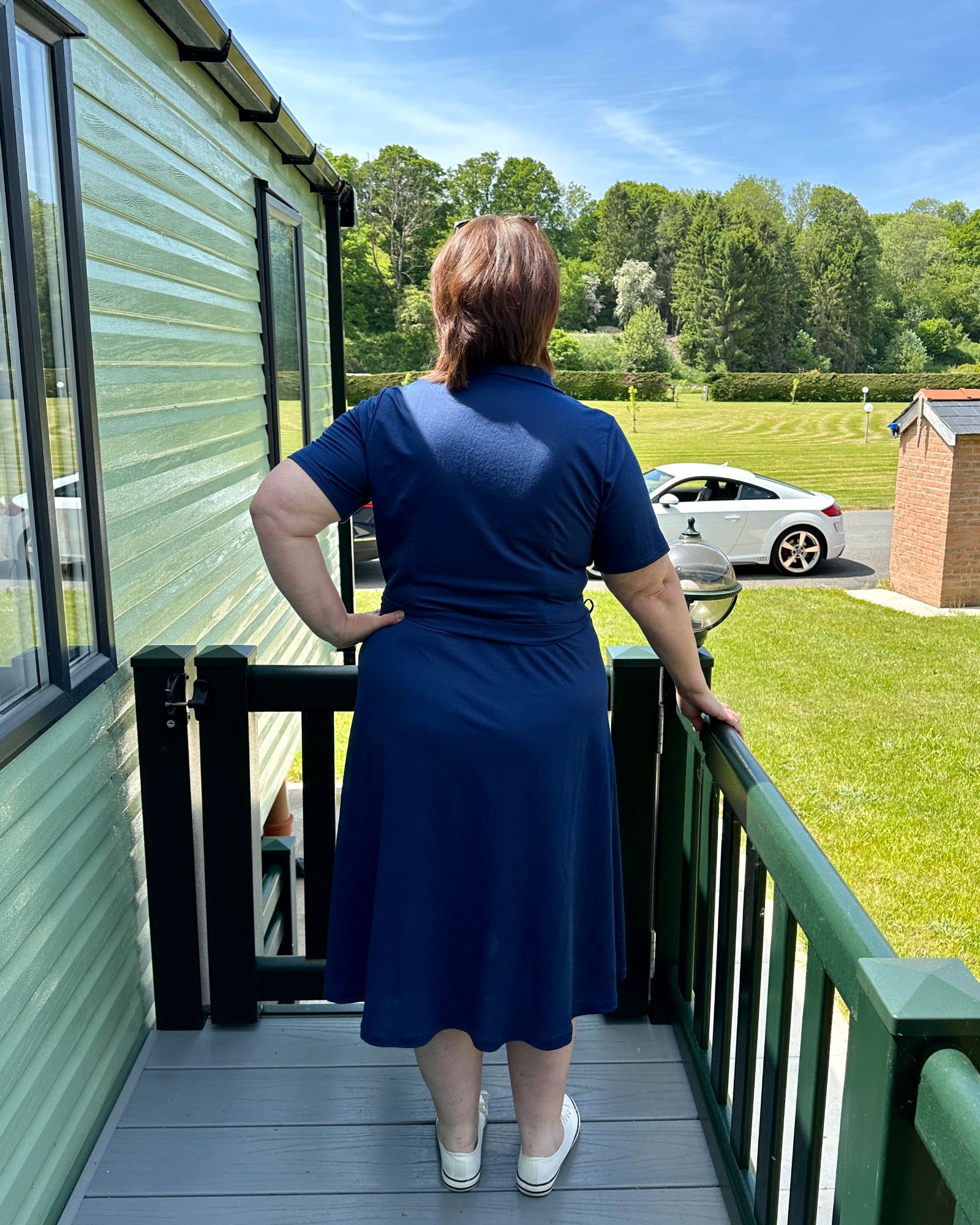 A lady with short brown hair with her back to the camera wearing a navy jersey dress