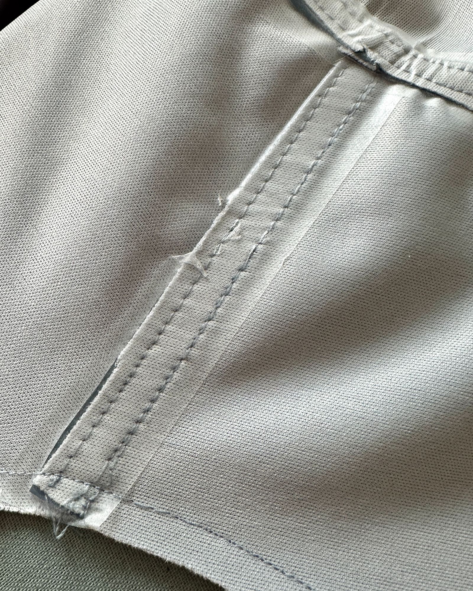 A stitched seam inside a coat shown with clear water proof tape stuck over the stitch lines