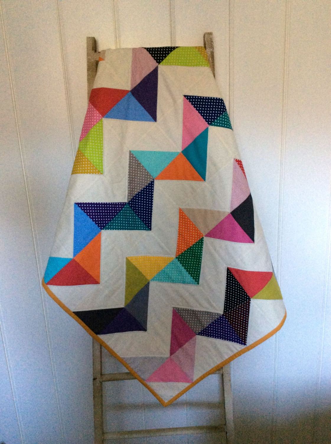 A brightly coloured quilt using Moda Dottie Charm Packs in a chevron ...