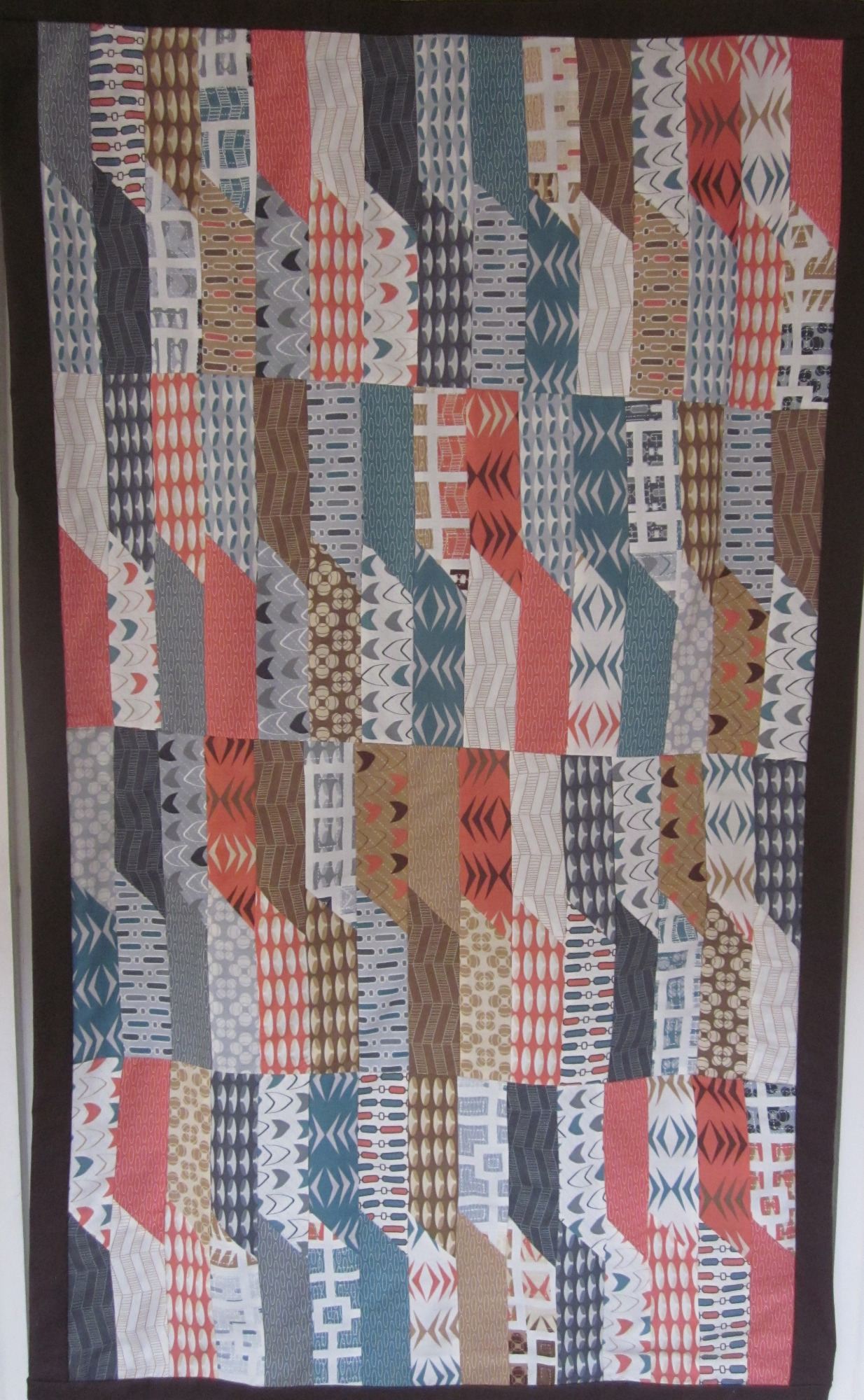 A Jelly Roll Wall Hanging Made With Modern Geometric Patterned Fabric.