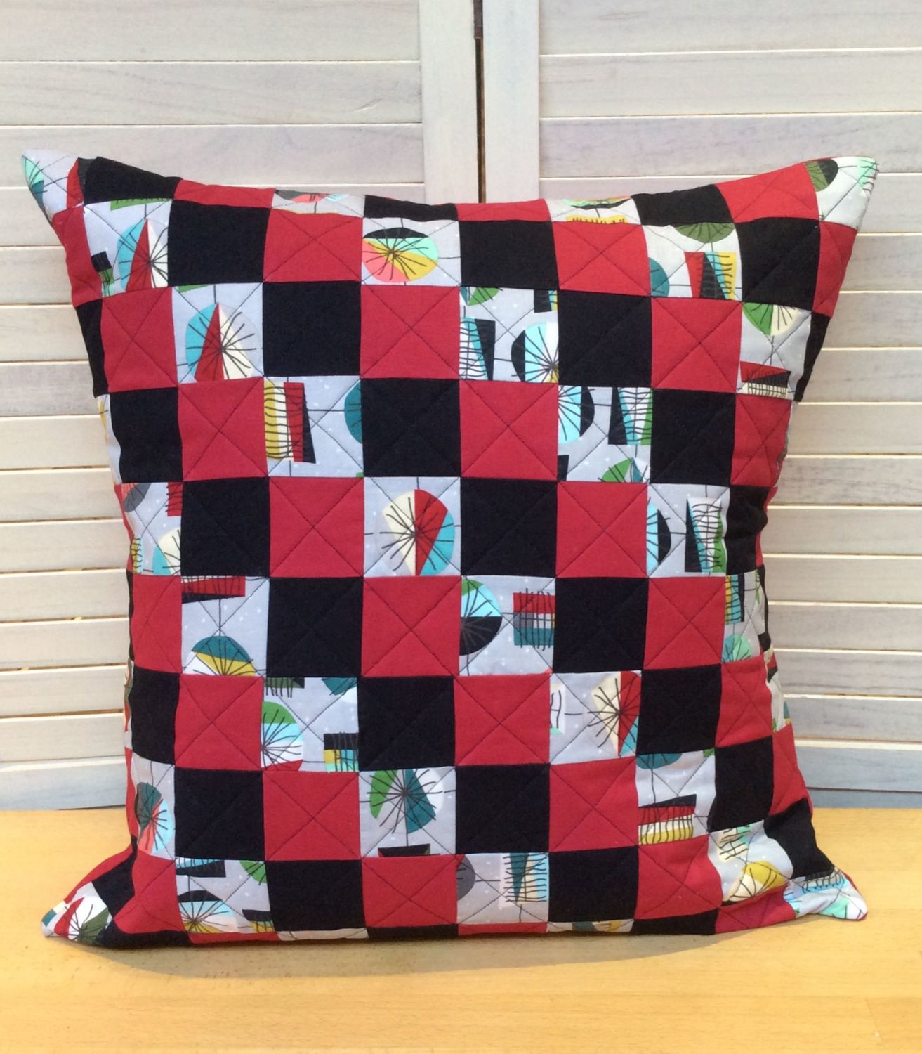 An eye catching quilted patchwork cushion in a retro print called Mid Mod