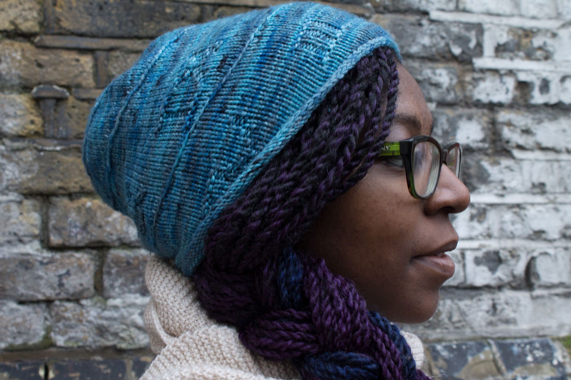 Girl with purple plaited hair wearing blue hat with Roman Numerals that spiral around the hat