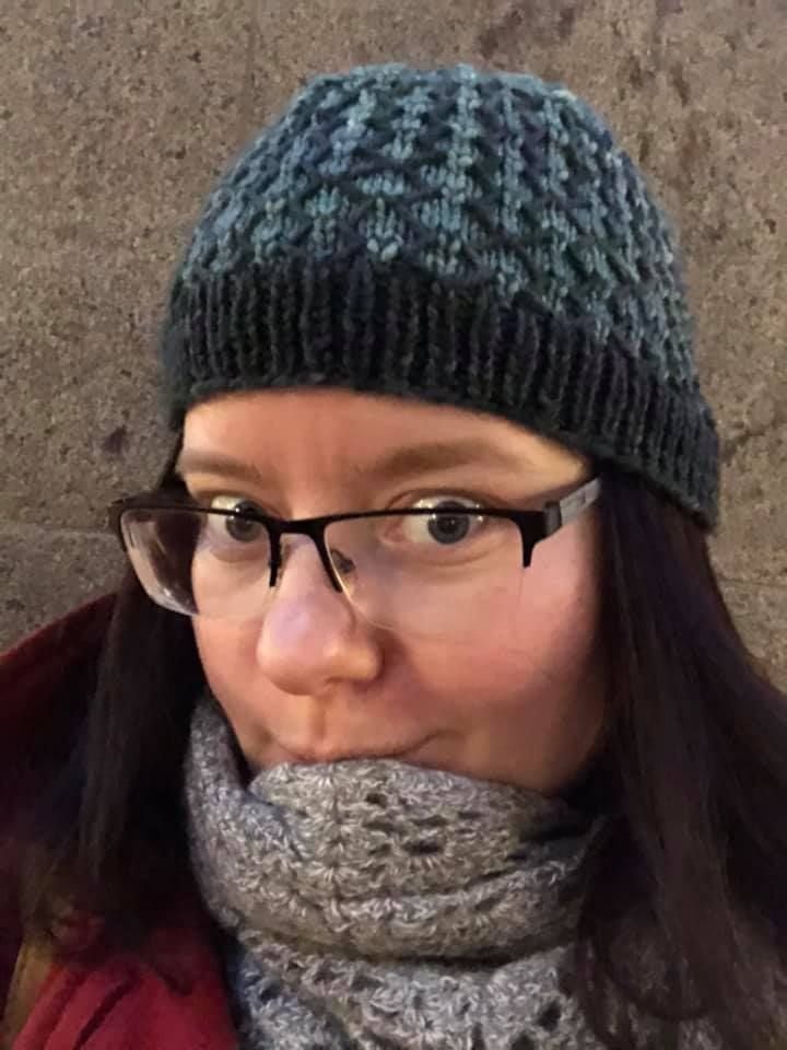 Brown haired woman wearing hat in blue and dark grey