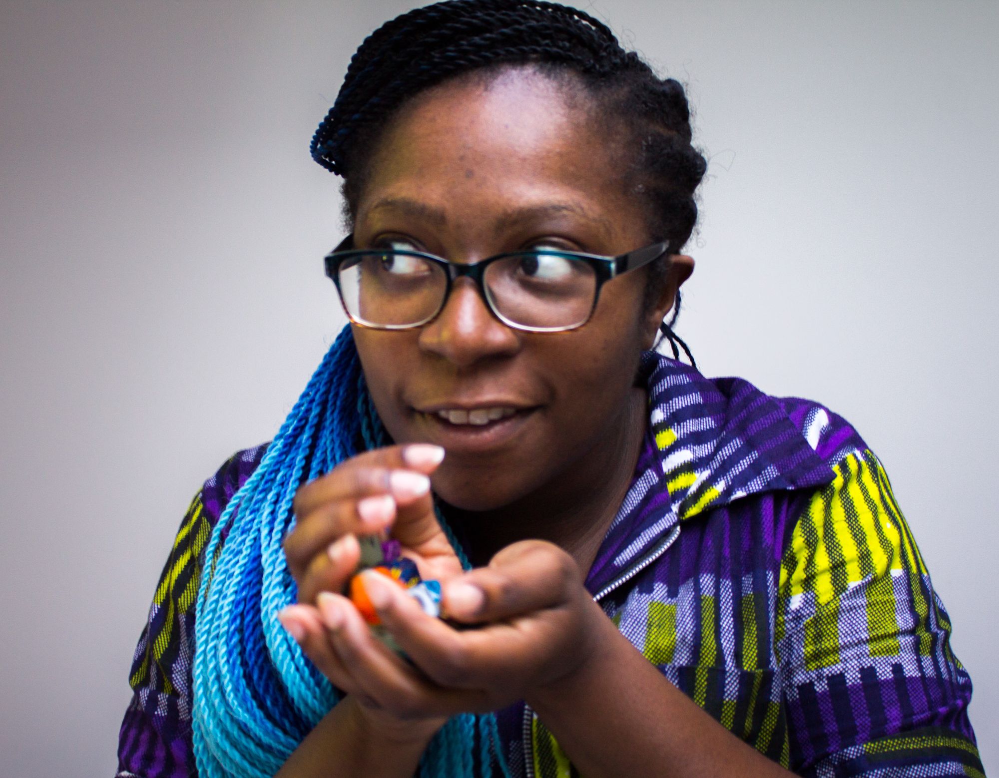 black person with black to blue gradietn twists, looking to the side cupping dice in their hands as if to hide them