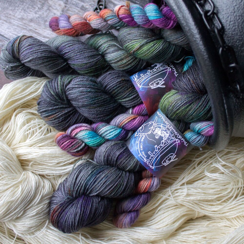 Grey yarn with speckles and splashes, bundled with mini skeins that are var