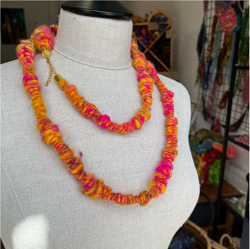 on a display mannequin is a double loopes yellow, orange and bright pink coiled fibre necklace