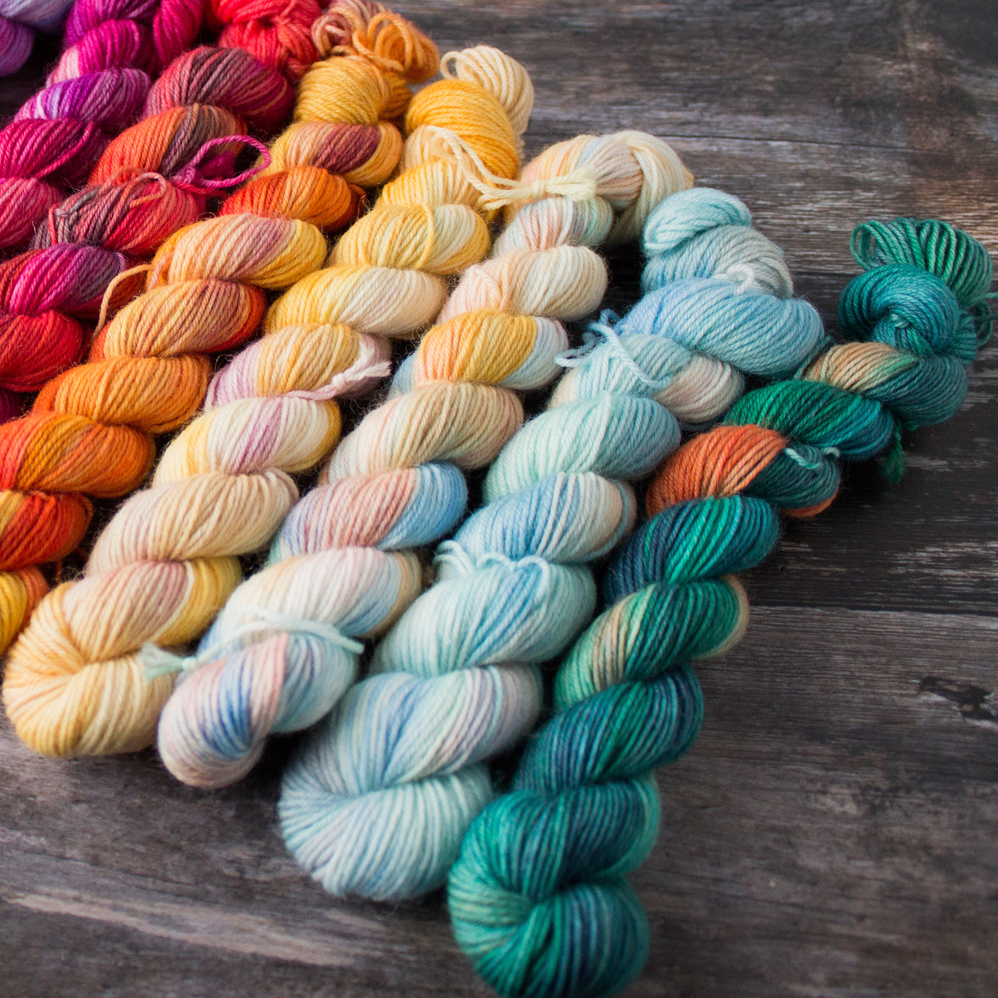 a close up focus on 5 mini skeins travelling in colour from teal blue, orange to red