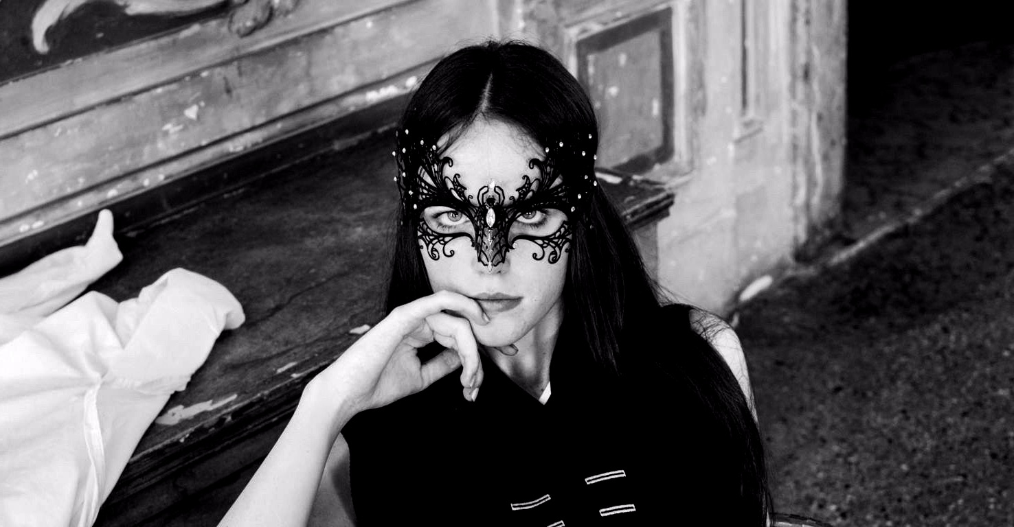 woman with black hair wearing a black filigree mask