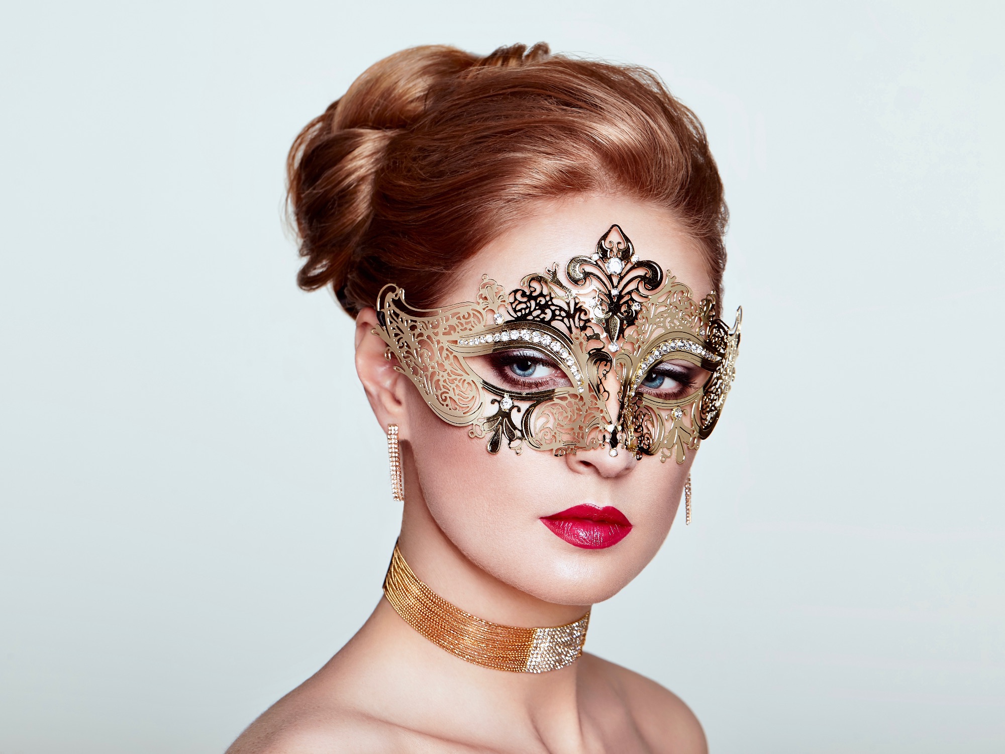 blonde haired woman wearing a gold filigree masquerade mask