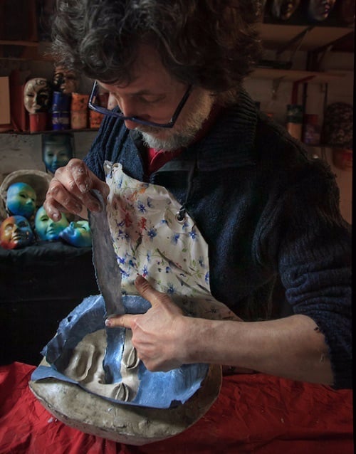 A man making a masquerade mask in a shop