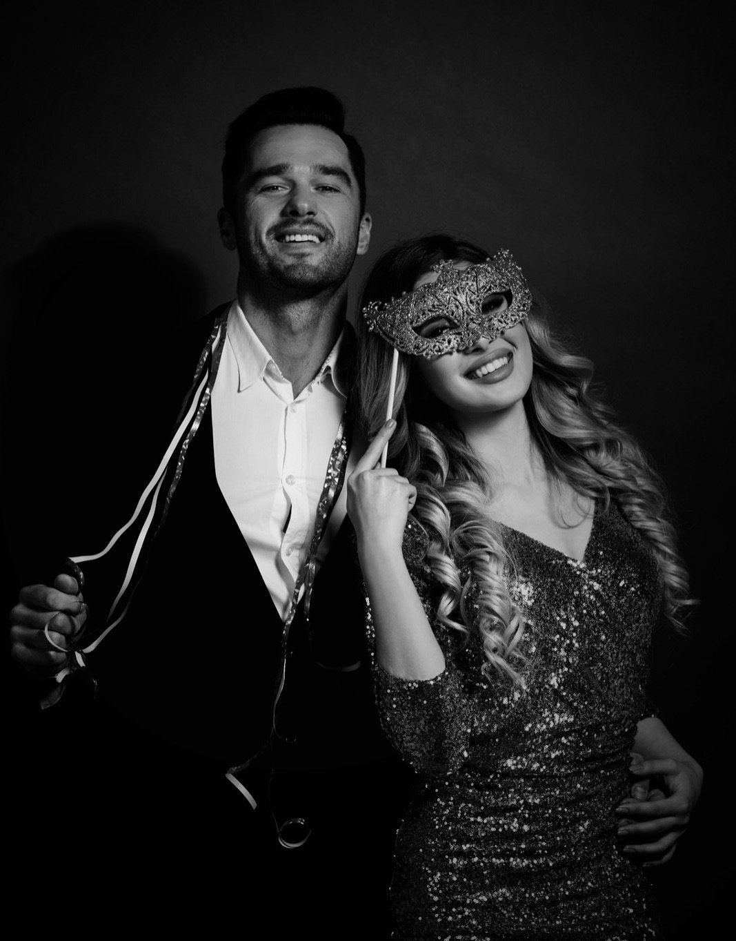 young couple in nice clothes and holding a mask at a Masquerade Ball
