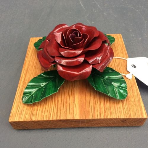 Dark red steel metal rose on an oak plinthe