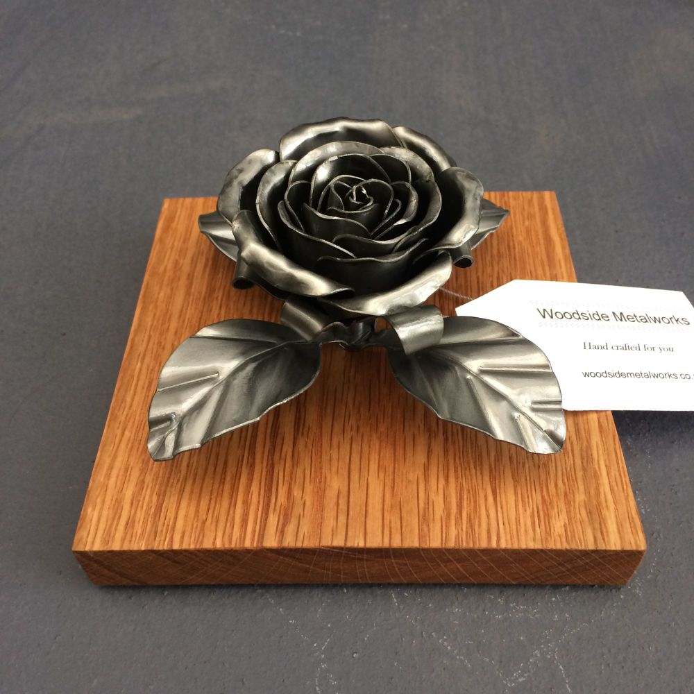 Steel metal rose on an oak plithe