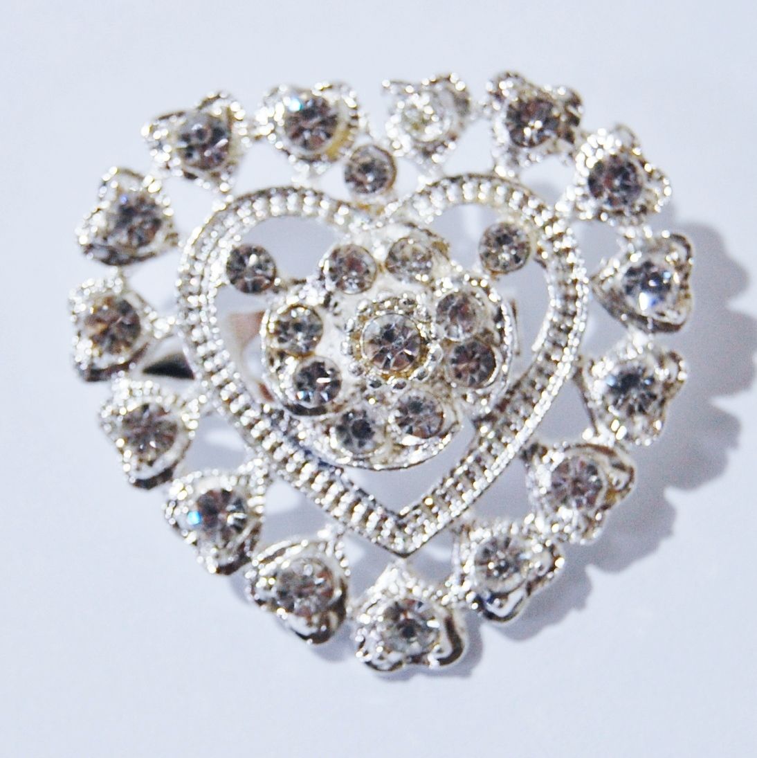 SILVER METAL AND JEWELLED HEART BROOCH.