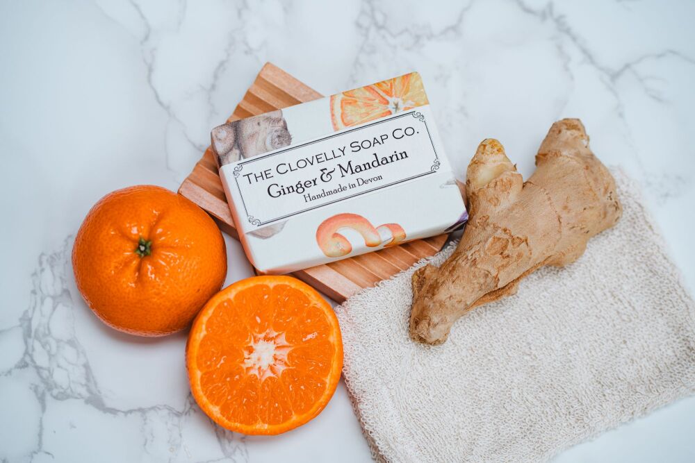 Ginger and Mandarin soap surrounded by Oranges and Ginger root on a soap dish