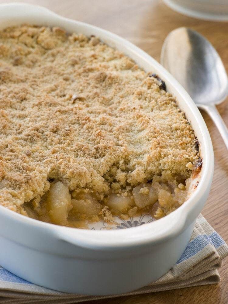 Bramley Apple Crumble served in a crash dish next to a spoon.