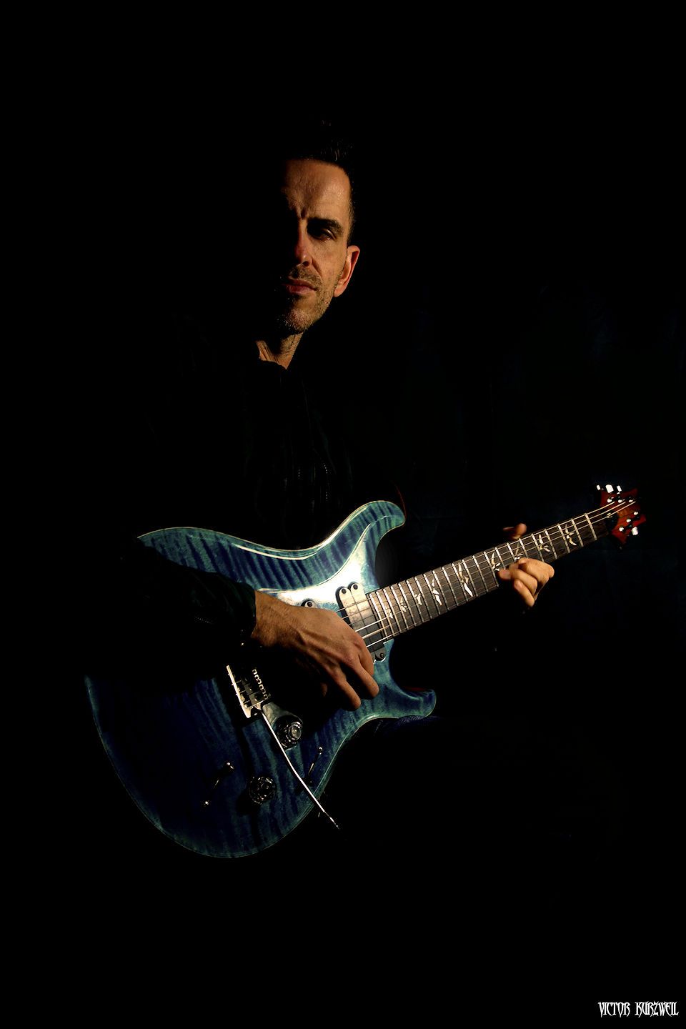 James Roberts with guitar on black back