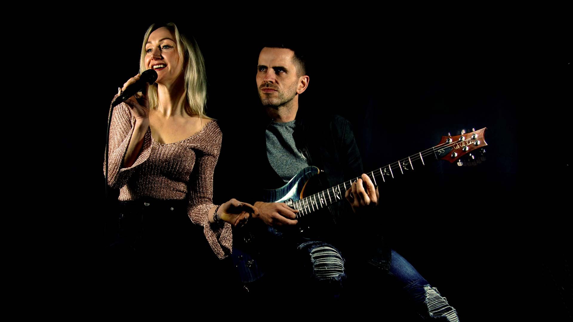 Glow Band Michelle and James on Black with guitar and mic