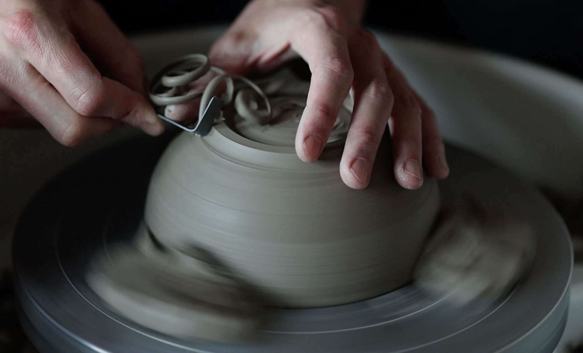 Hands trimming a ceramic bowl