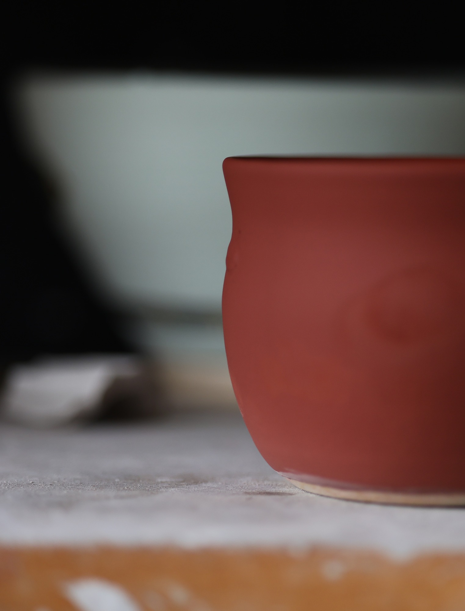 Wheel thrown pot on a shelf with red glaze