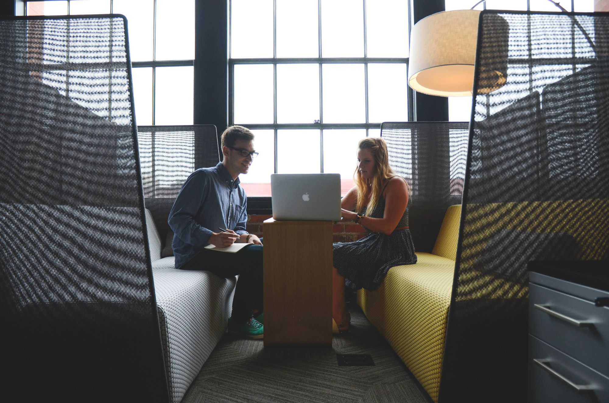 Being progressive - A man and a woman looking at the same laptop in front of a big window