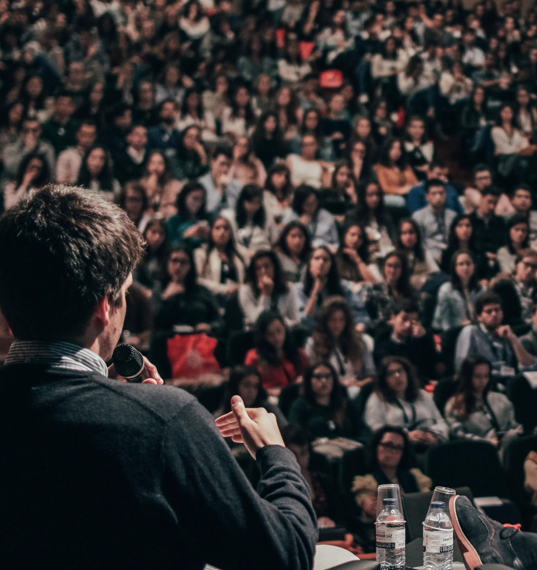 An image shot behind a man speaking to a large crowd