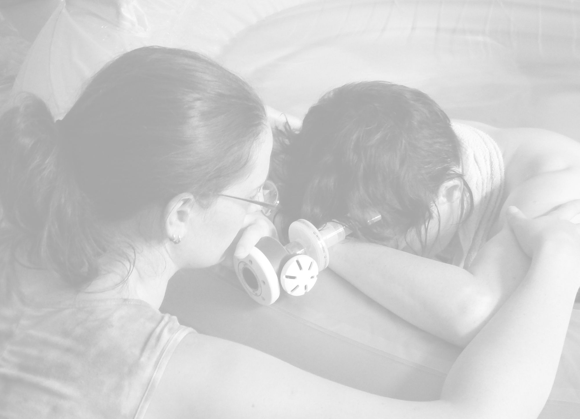 Black and white image of Caz comforting a labouring woman in a birth pool