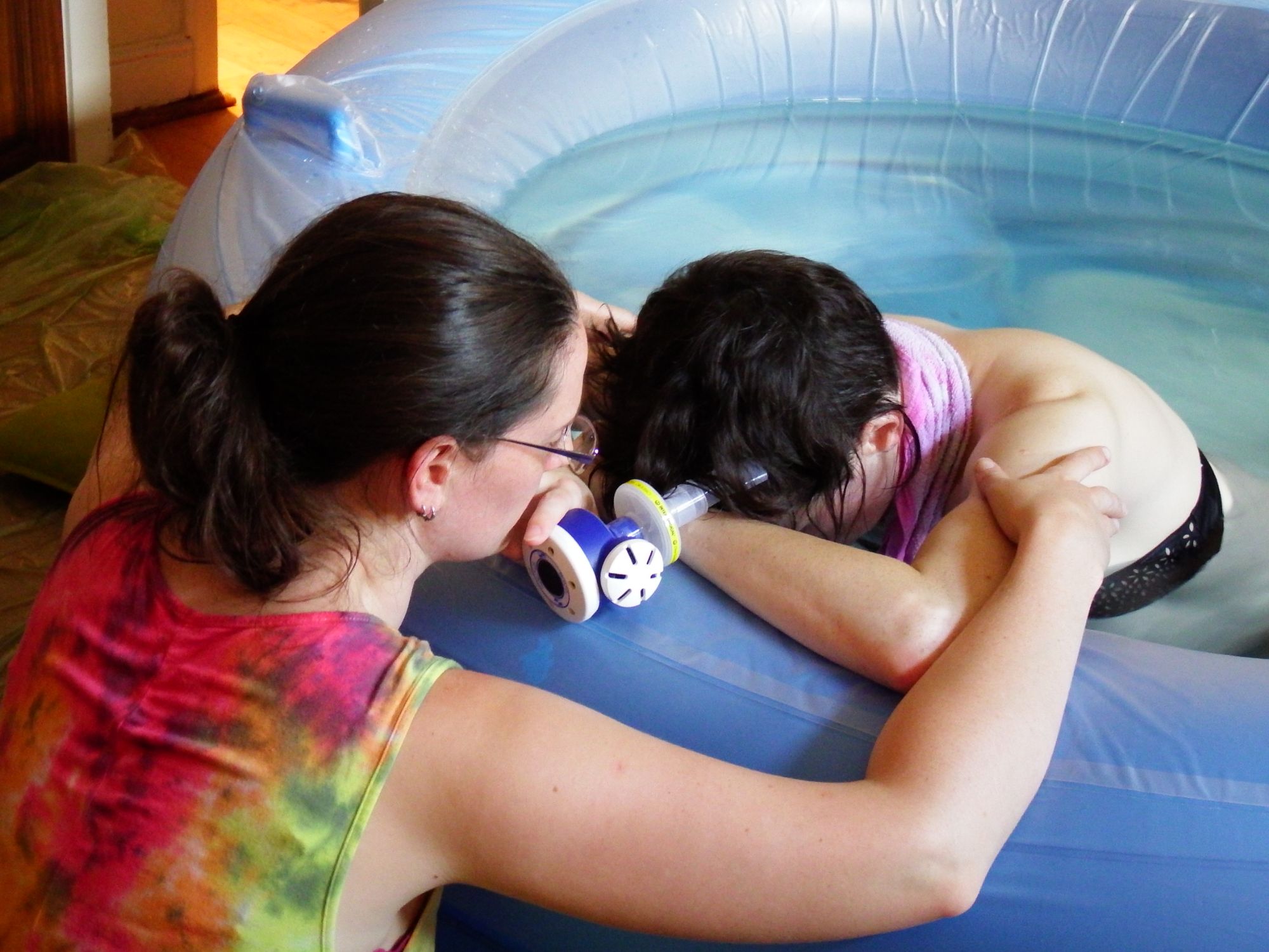 Image of Caz with her arms round a labouring woman in a birth pool.