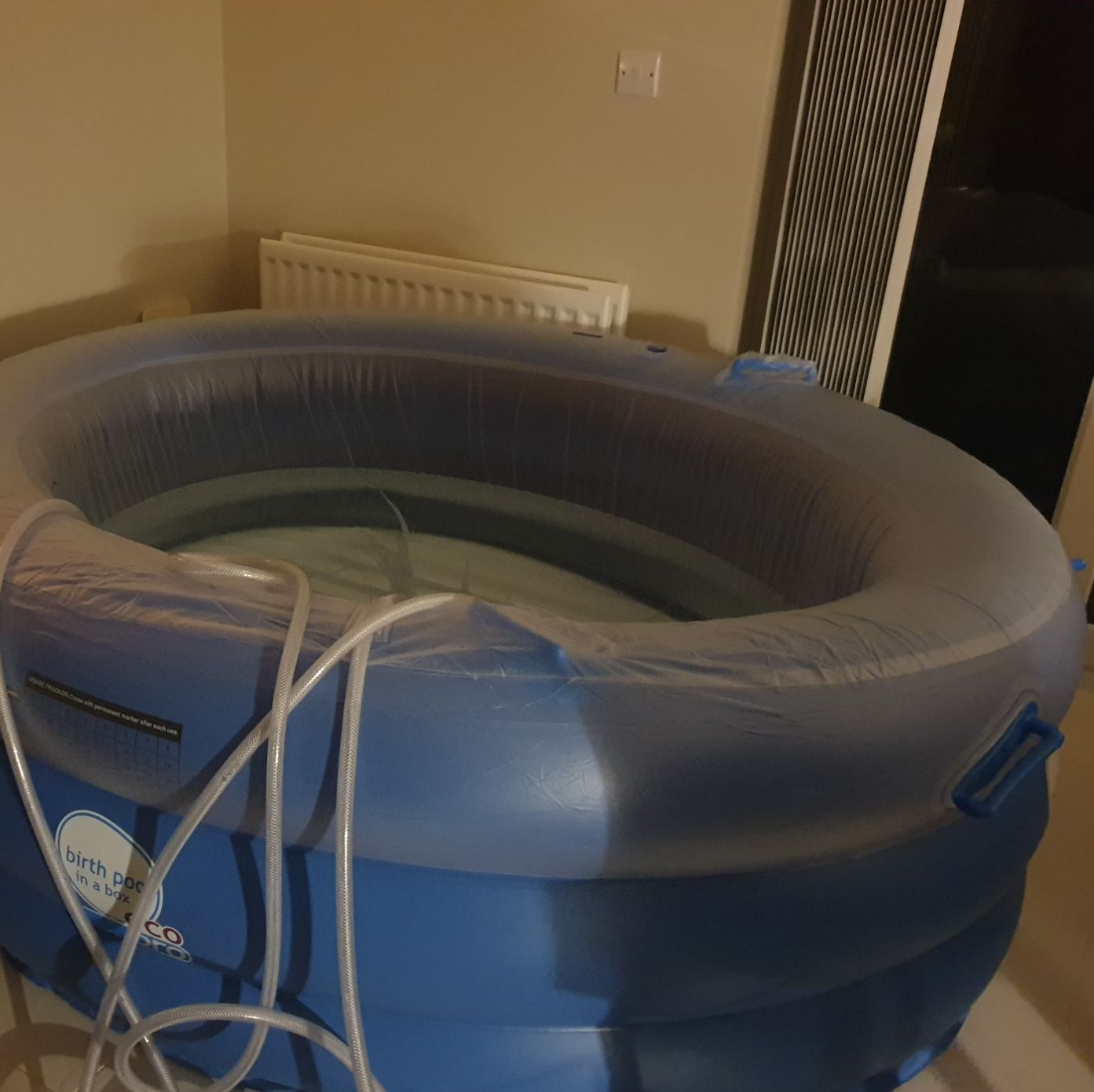 A regular pool in a client's kitchen. It is filled with water and the hose is draped over the side.