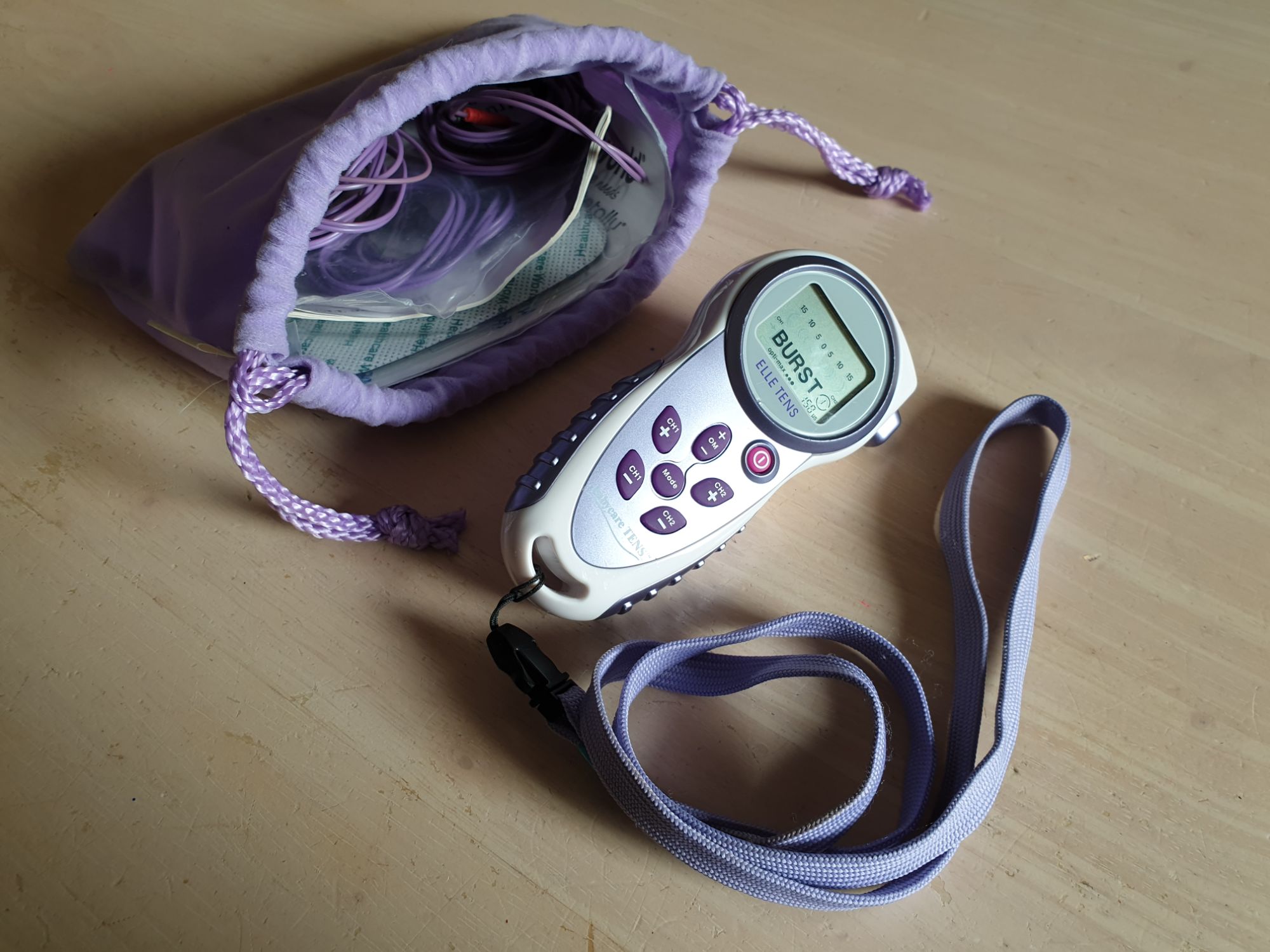 A TENS machine and cloth bag on a table.