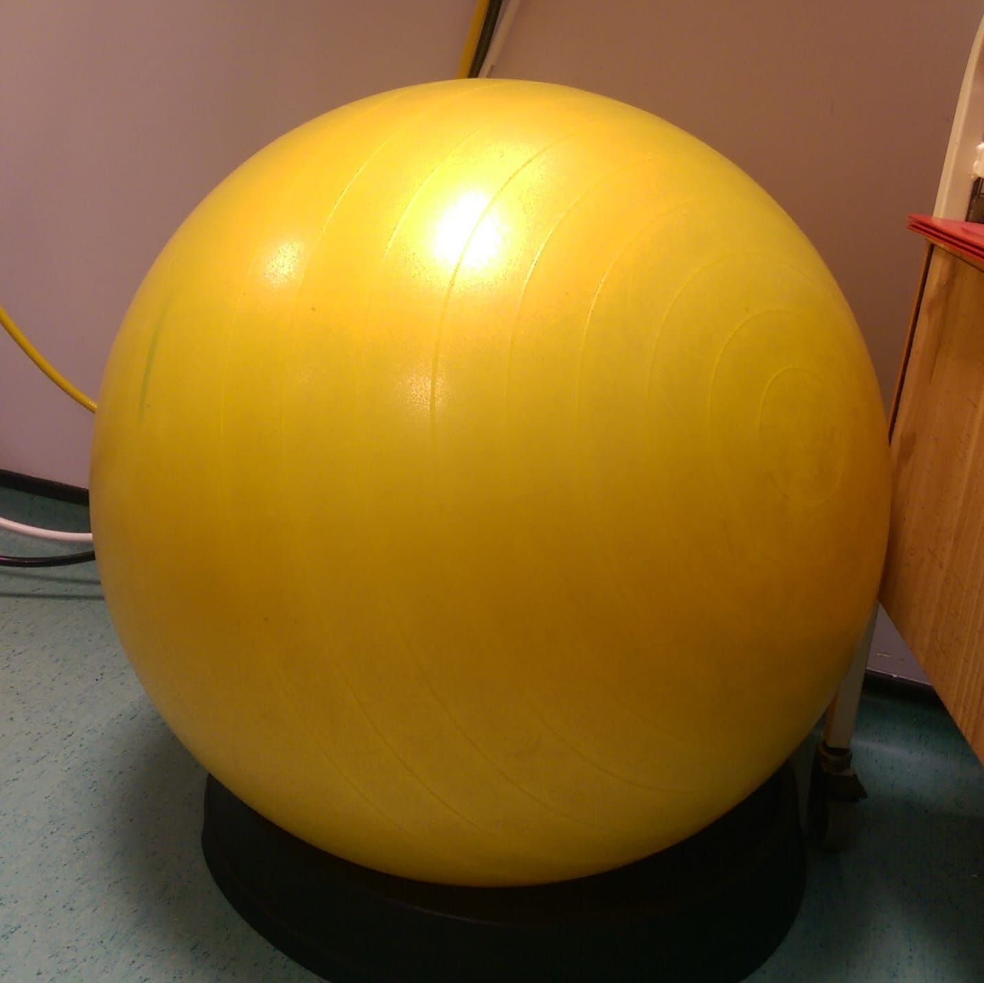 A woman sitting in a birth pool holding a newborn baby. The water is illuminated blue from the submersible light in the water.
