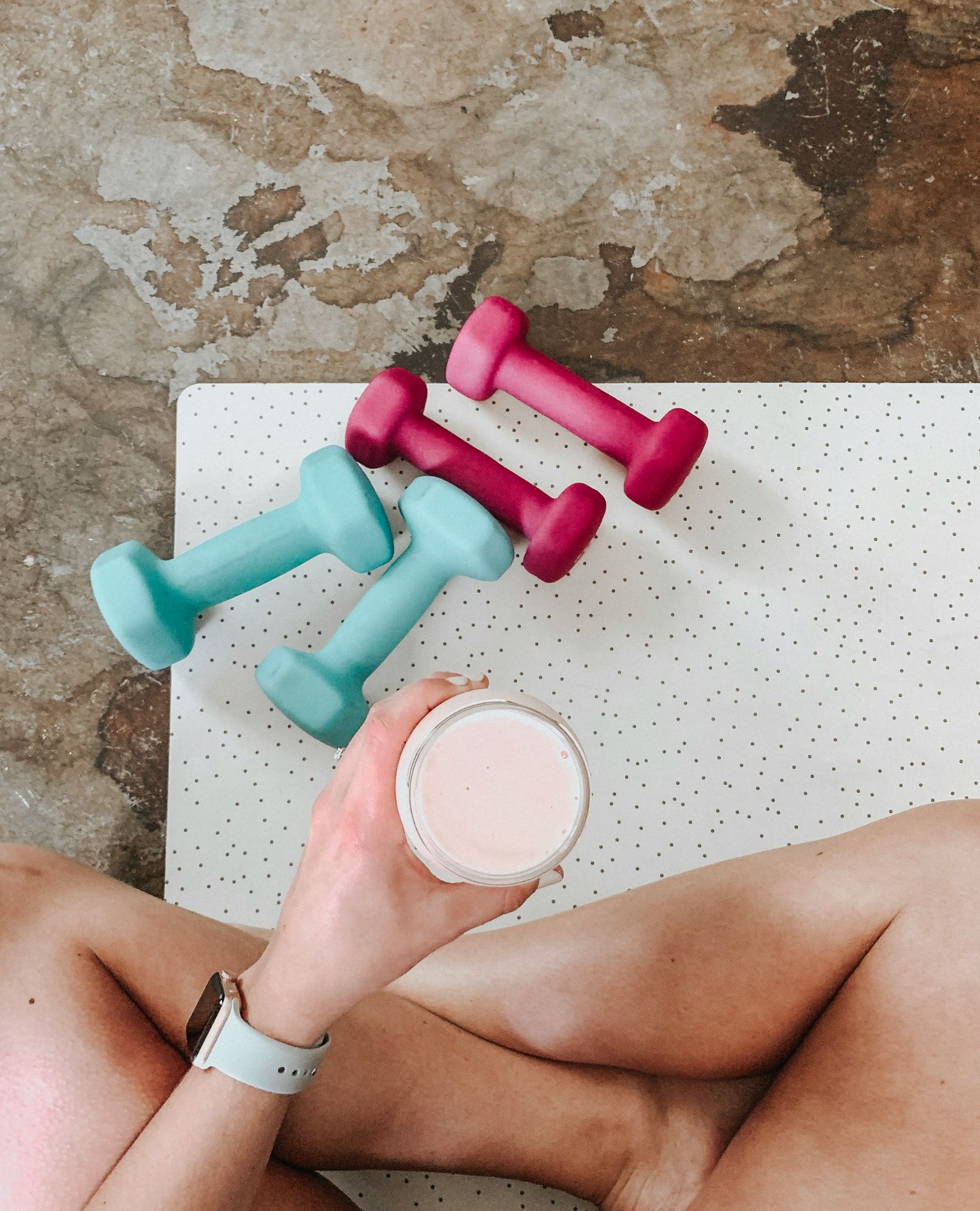 person-holding-white-liquid-filled-cup-above-two-pairs-of-dumbbells-__QqvTI