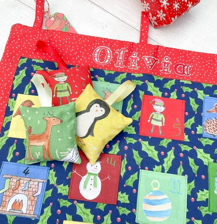 Lavender bag with Christmas picutres on against a fabric personalised Christmas advent calendar with pockets