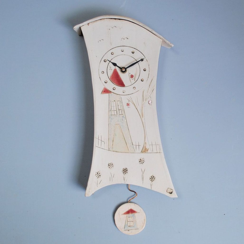 Ceramic wall clock from white clay with house motif and pendulum.