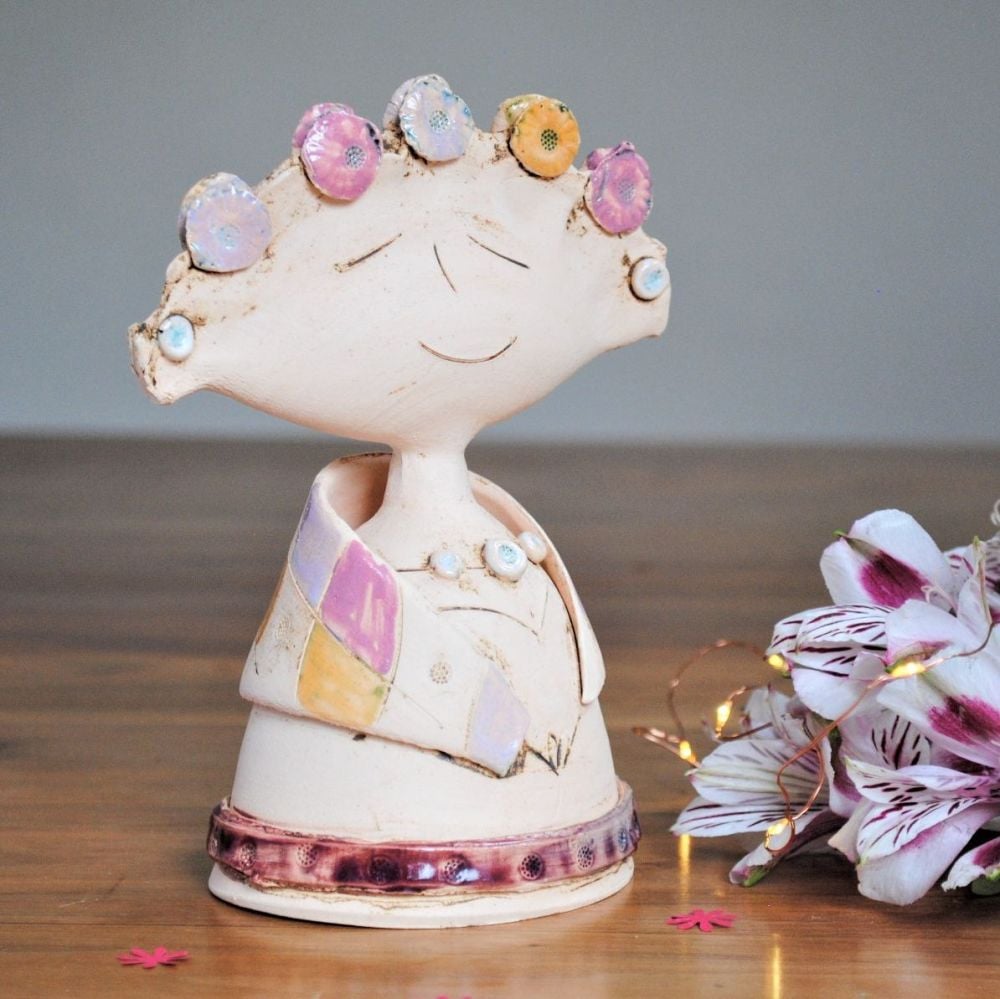 Lady sculpture with pink, purple and yellow flowers.