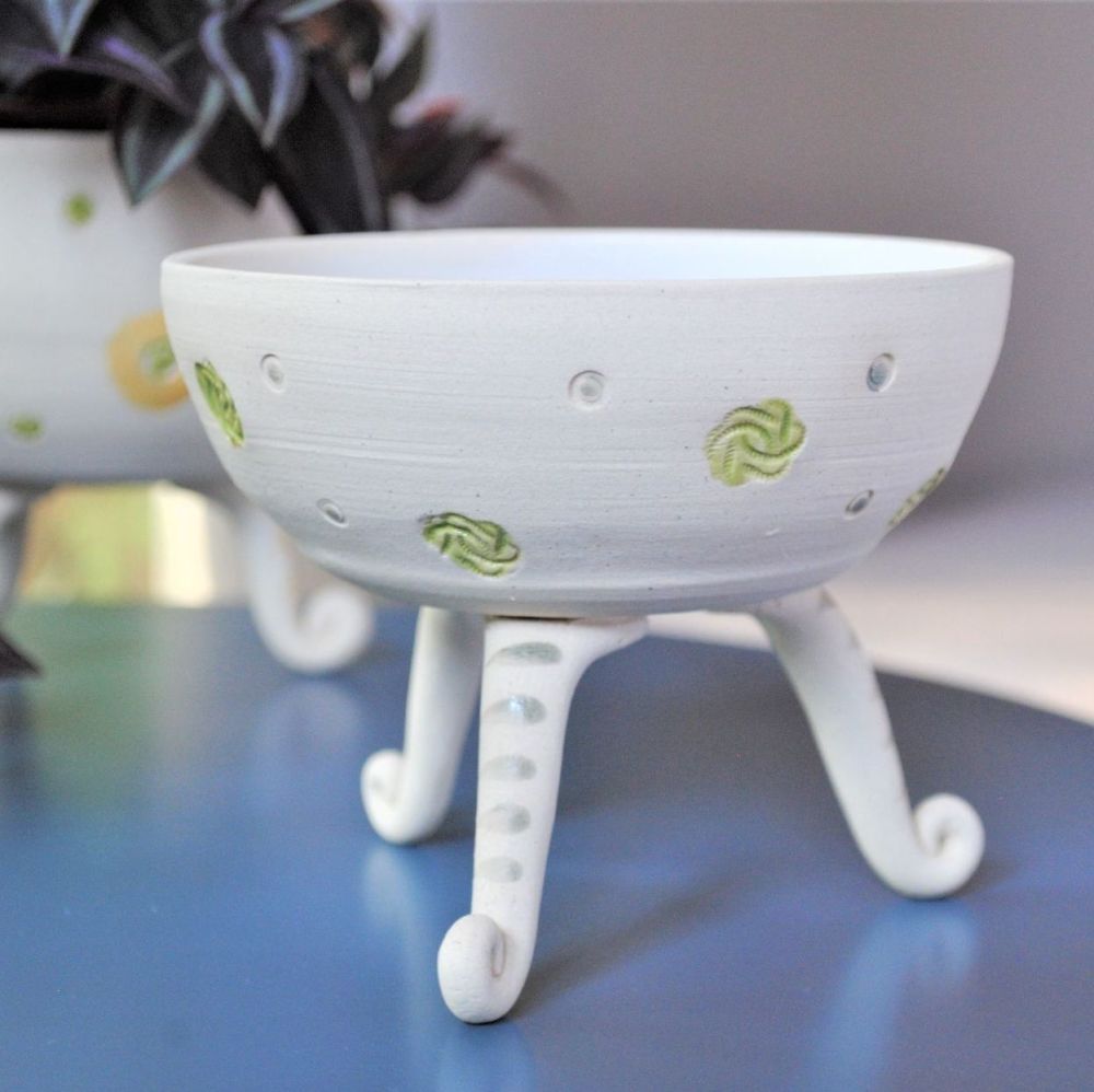 white ceramic bowl with feet and green and purple details.