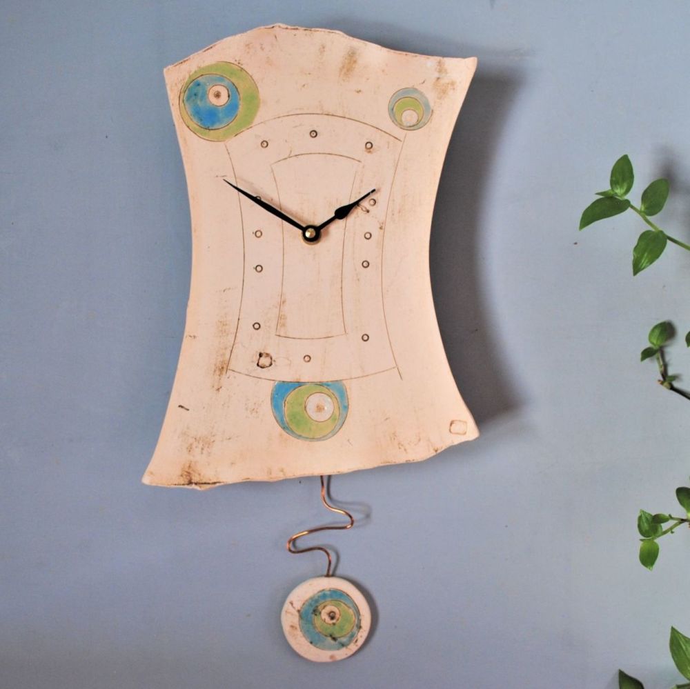 Ceramic pendulum wall clock with dots and circles.
