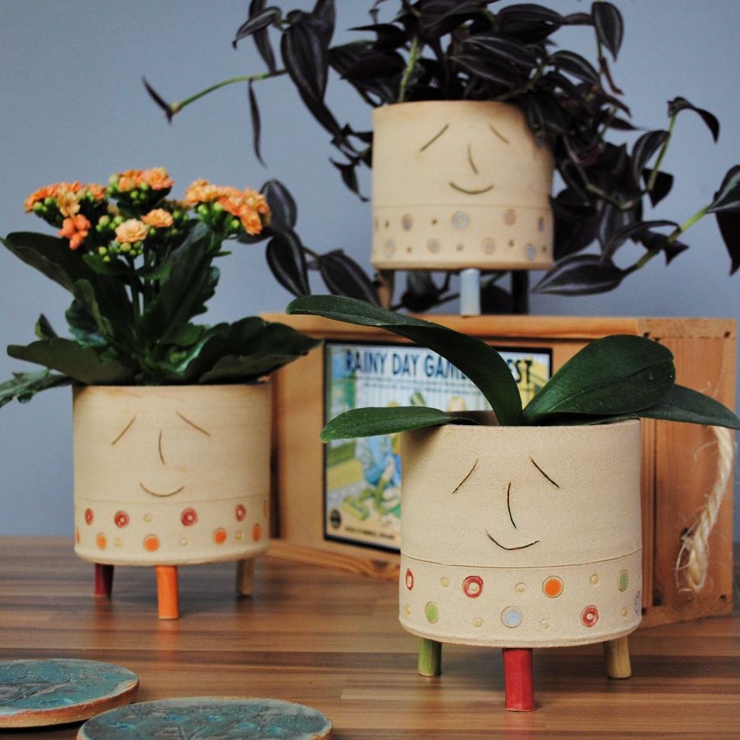 Spotty stoneware plant pots with smiley faces and legs.  