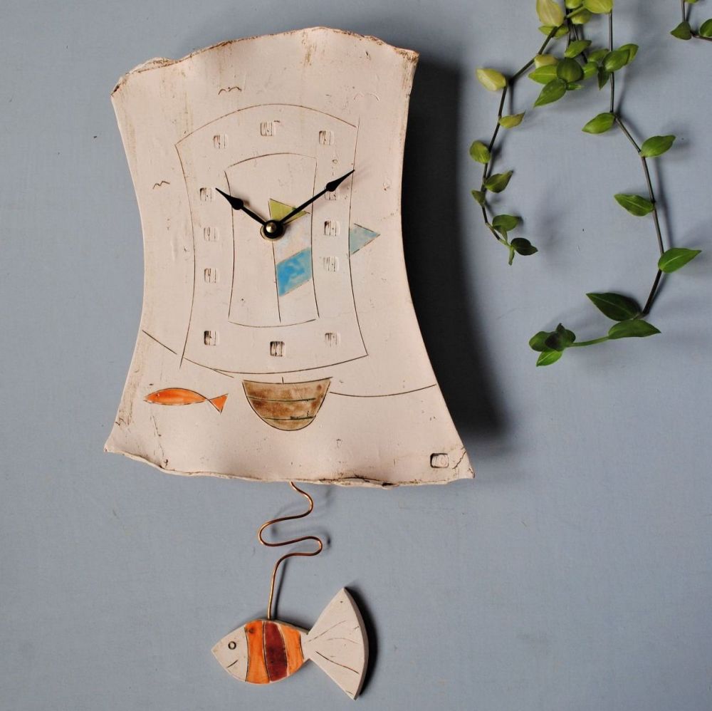Handmade ceramic pendulum wall clock with boat and fish design.