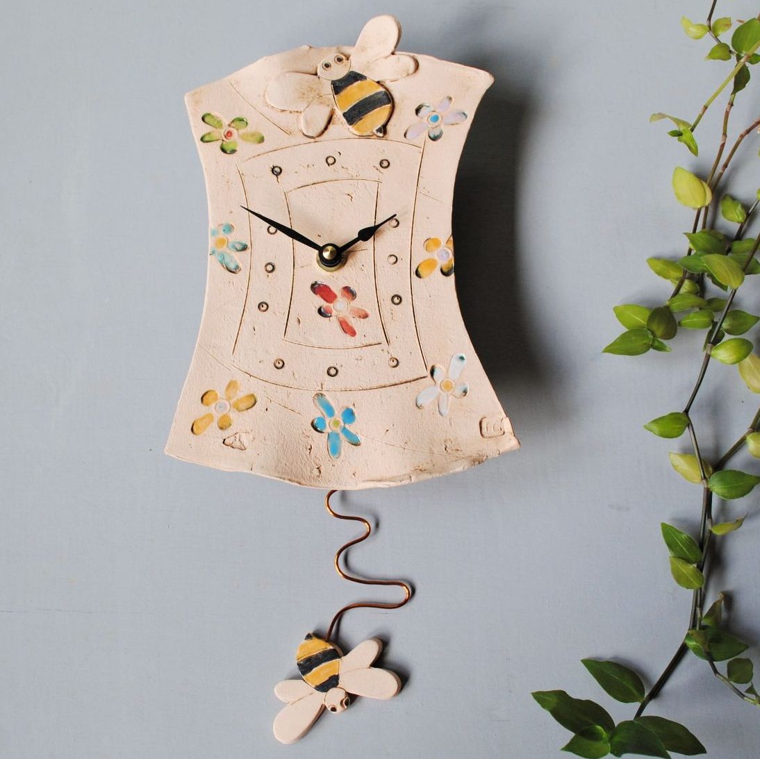Ceramic pendulum wall clock with flowers and bee as pendulum.