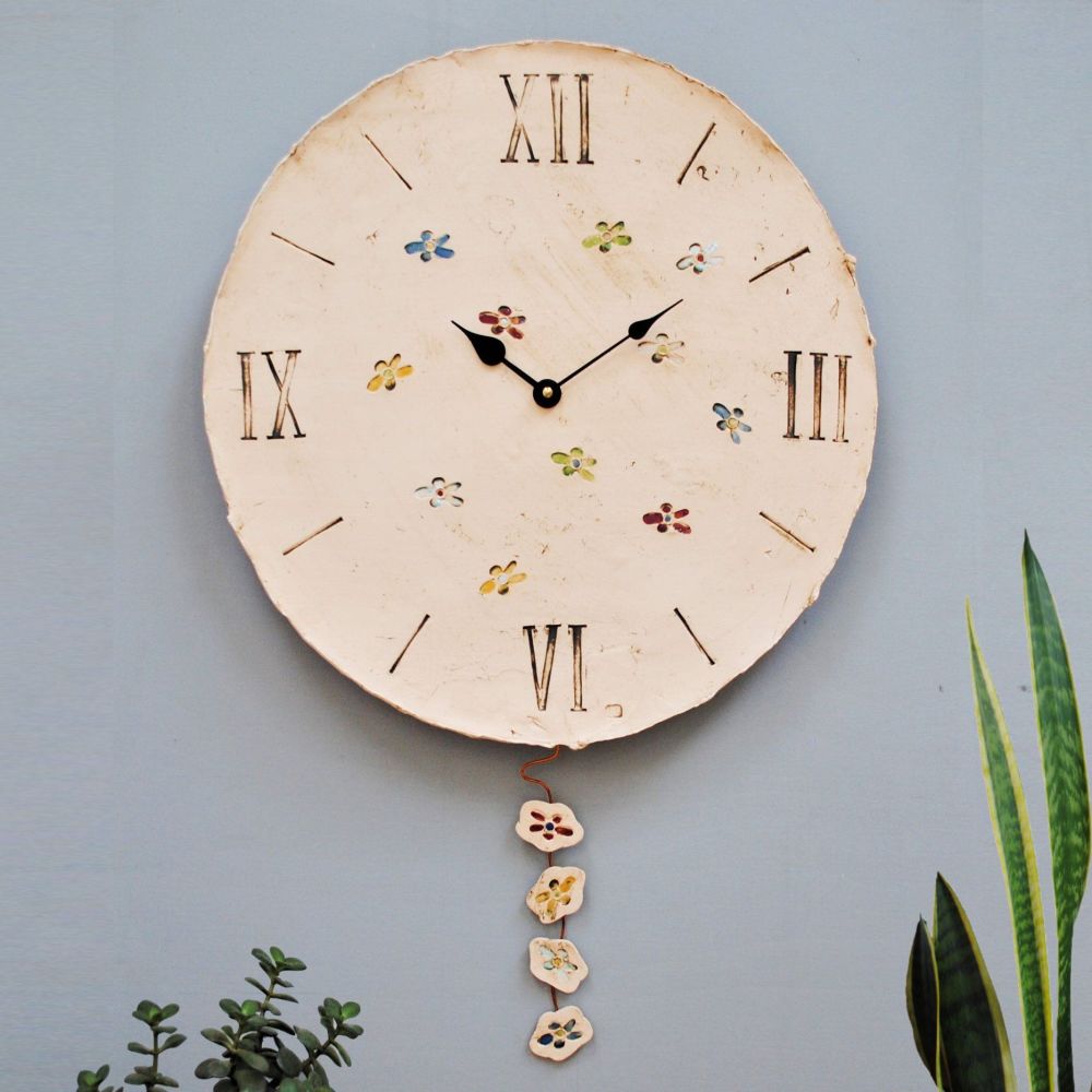 Ouversized wall clock with flower design and pendulum.