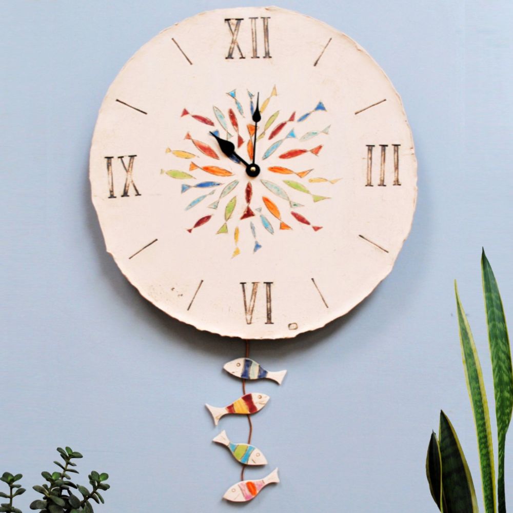 Large round wall clock with fish and pendulum.