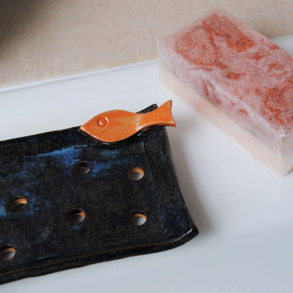 Navy blue soap dish with orange fish decor.