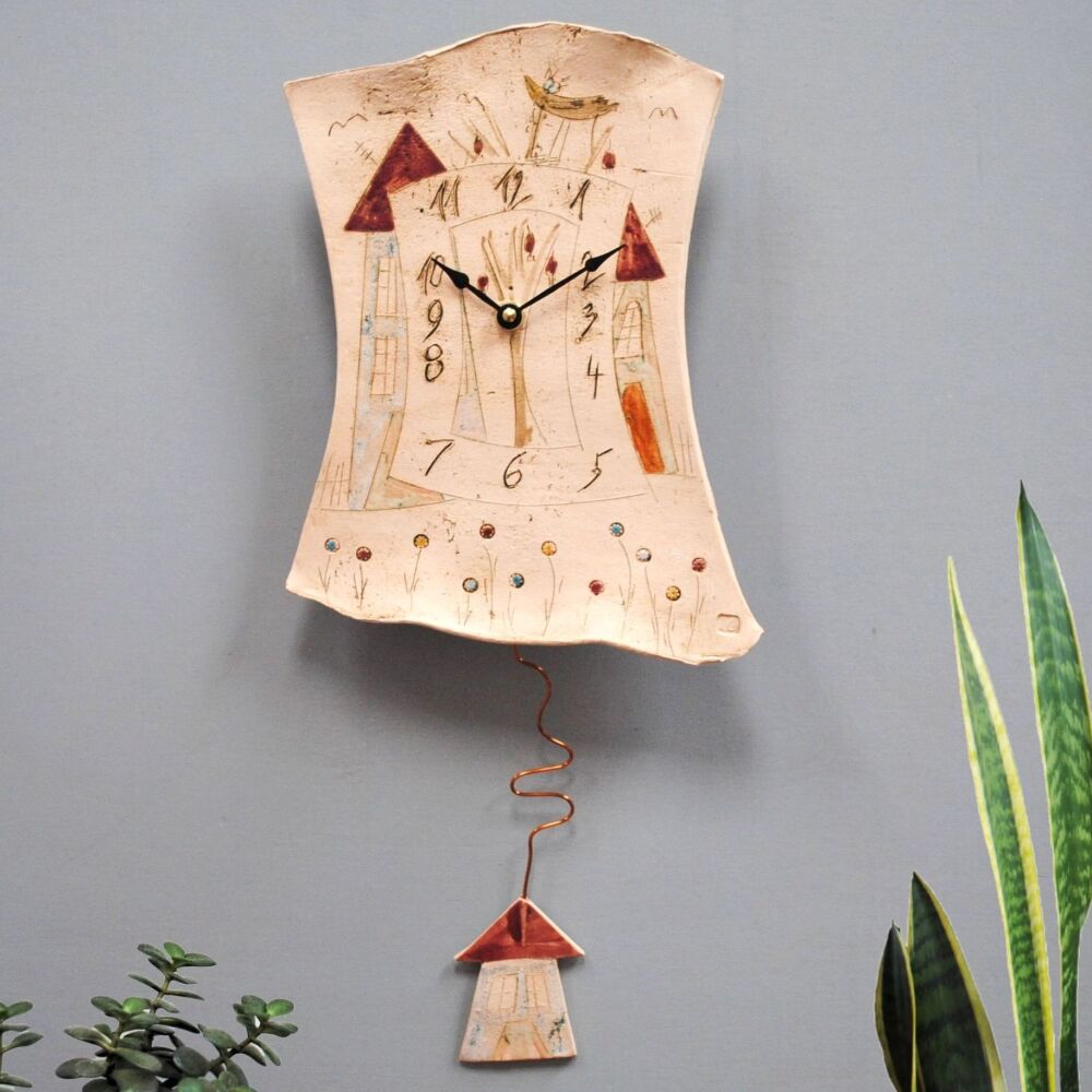 Ceramic pendulum wall clock with houses, trees and meadow.