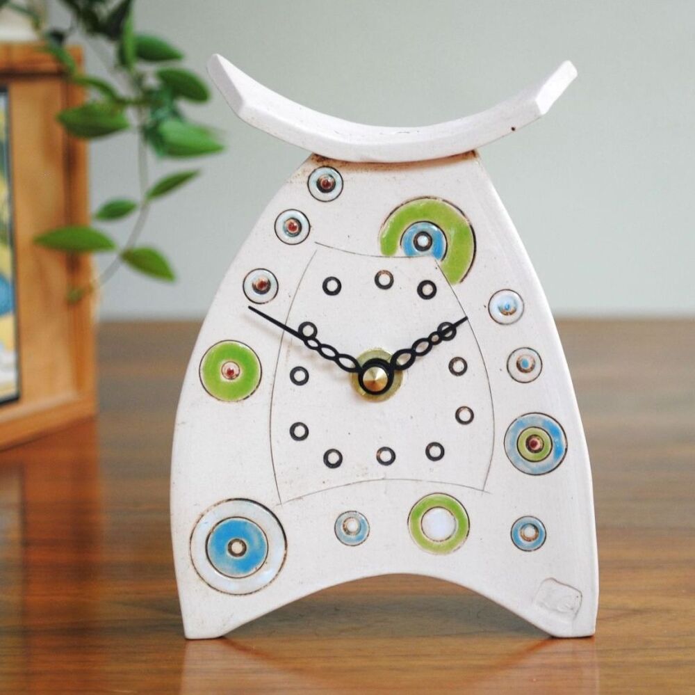 Small ceramic clock white with green and blue details.