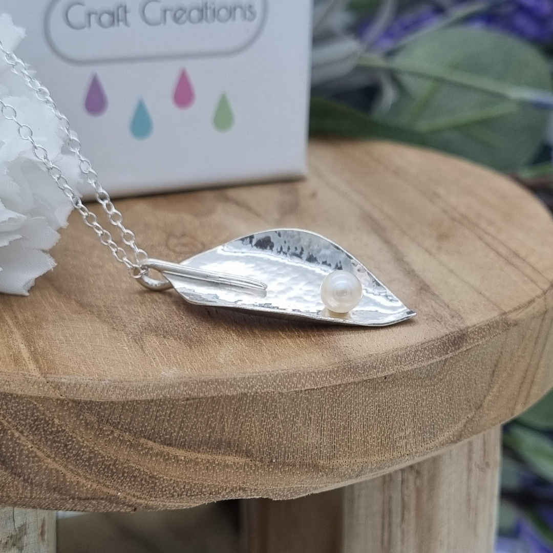 A bespoke sterling silver necklace in a curved leaf design featuring a freshwater milky pearl, an special 30th anniversary piece handmade by Streets Craft Creations