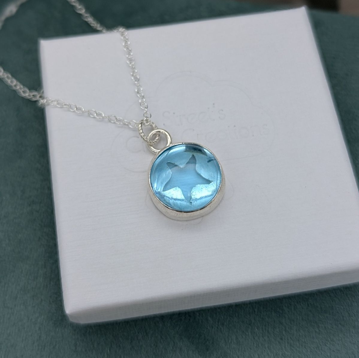Aqua blue glass starfish necklace on a white jewellery box