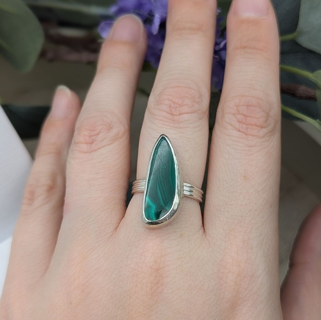 A free form malachite gemstone ring being modelled on a hand
