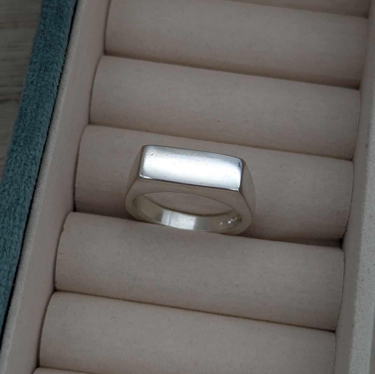 The top view of the signet ring in a jewellery box with a soft light that makes the piece shine 