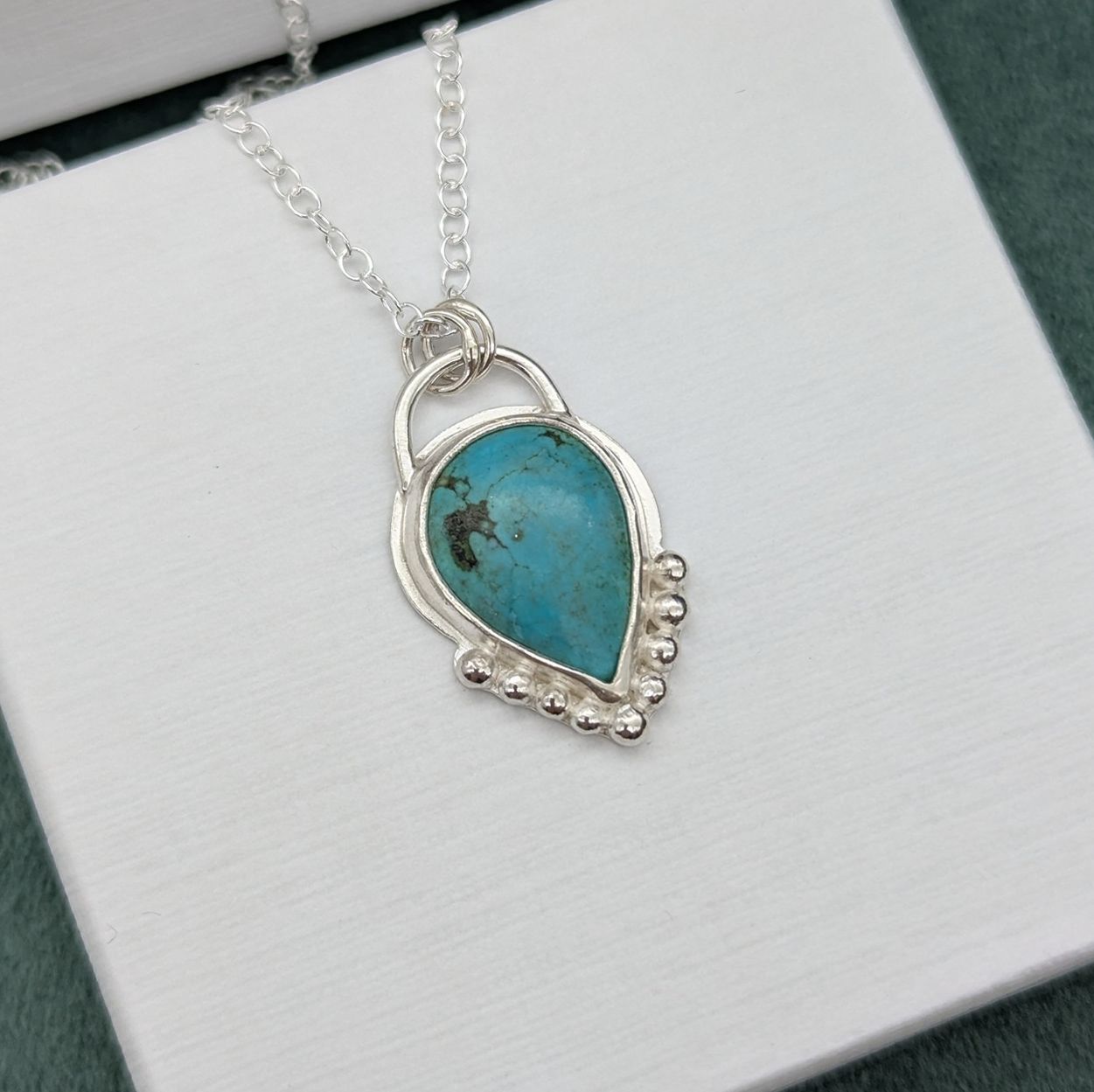 Silver & turquoise necklace resting on a white jewellery box